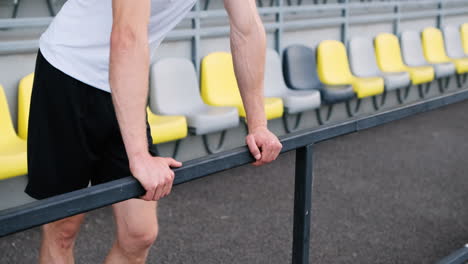 Müde-Fitness-Junger-Männlicher-Athlet-Ruht-Sich-Aus,-Während-Er-Sich-Auf-Metallgeländern-Im-Stadion-Lehnt