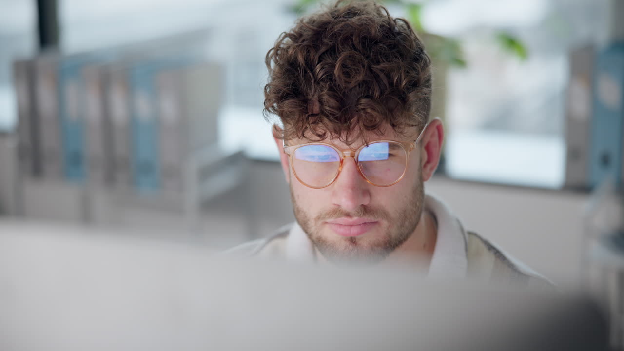 Man with curly hair working on a computer