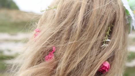 close up of cheerful flowers braided in a blond woman's hair