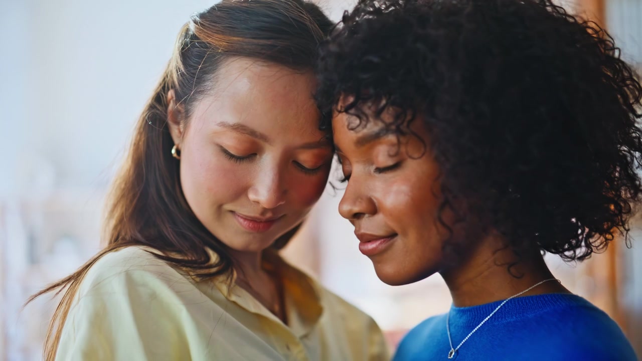 Pareja lésbica interracial tocándose las frentes. Primer plano de dos mujeres en un gesto de amor tierno