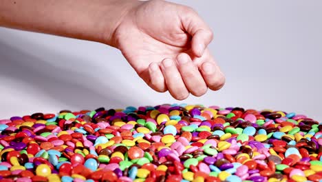 hand picking blue candies from colorful pile