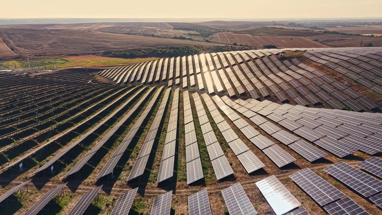 Solpaneler dækker et stort område på en vedvarende energipark med rækker opstillet i parallelle linjer i dagtimerne