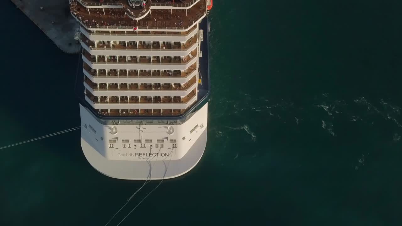 Aerial topdown view with sideways camera movement of a big cruise ship with people on the upper deck