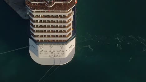 aerial topdown view with sideways camera movement of a big cruise ship with people on the upper deck