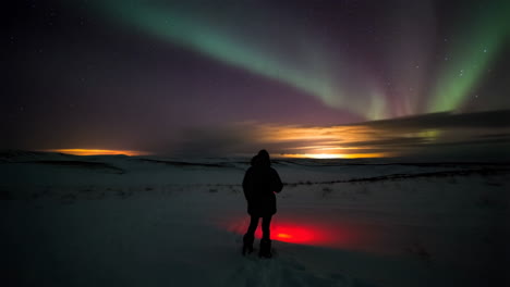 person watches the aurora borealis in a snowy landscape at night