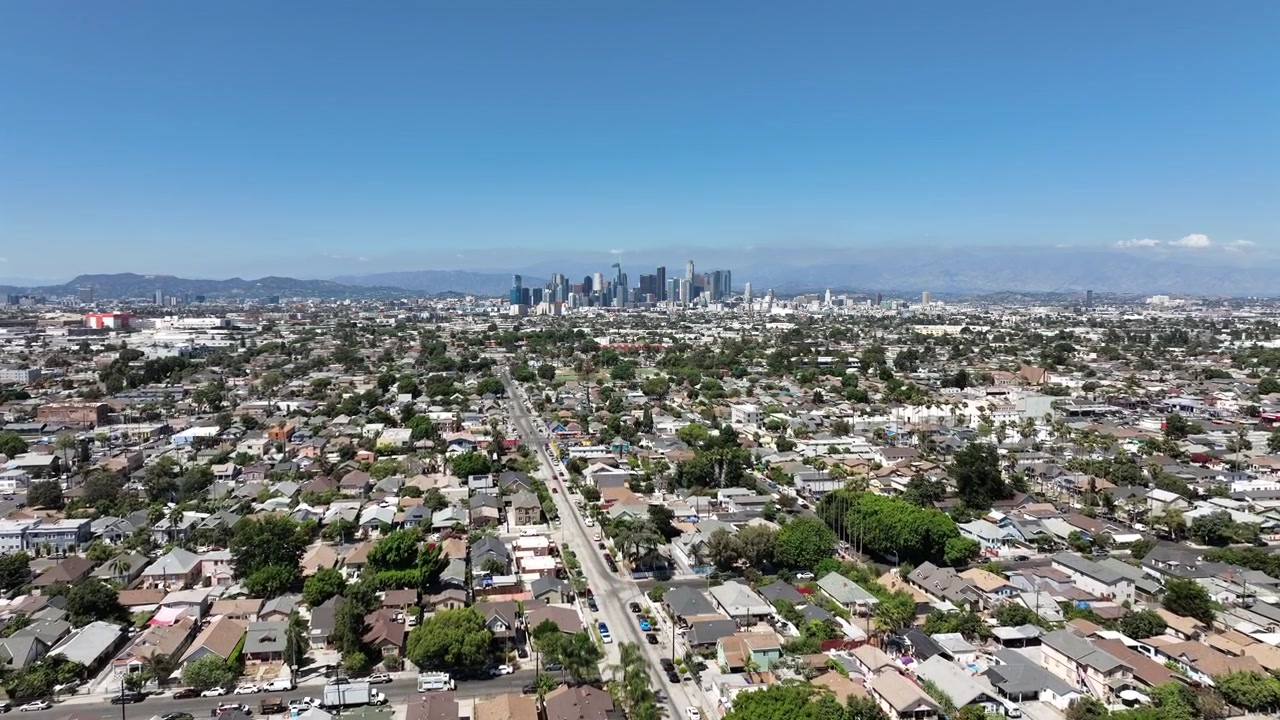 Riprese aeree che dominano lo skyline del centro di Los Angeles in una luminosa giornata estiva di sole, con alti edifici commerciali a più piani circondati da case residenziali.