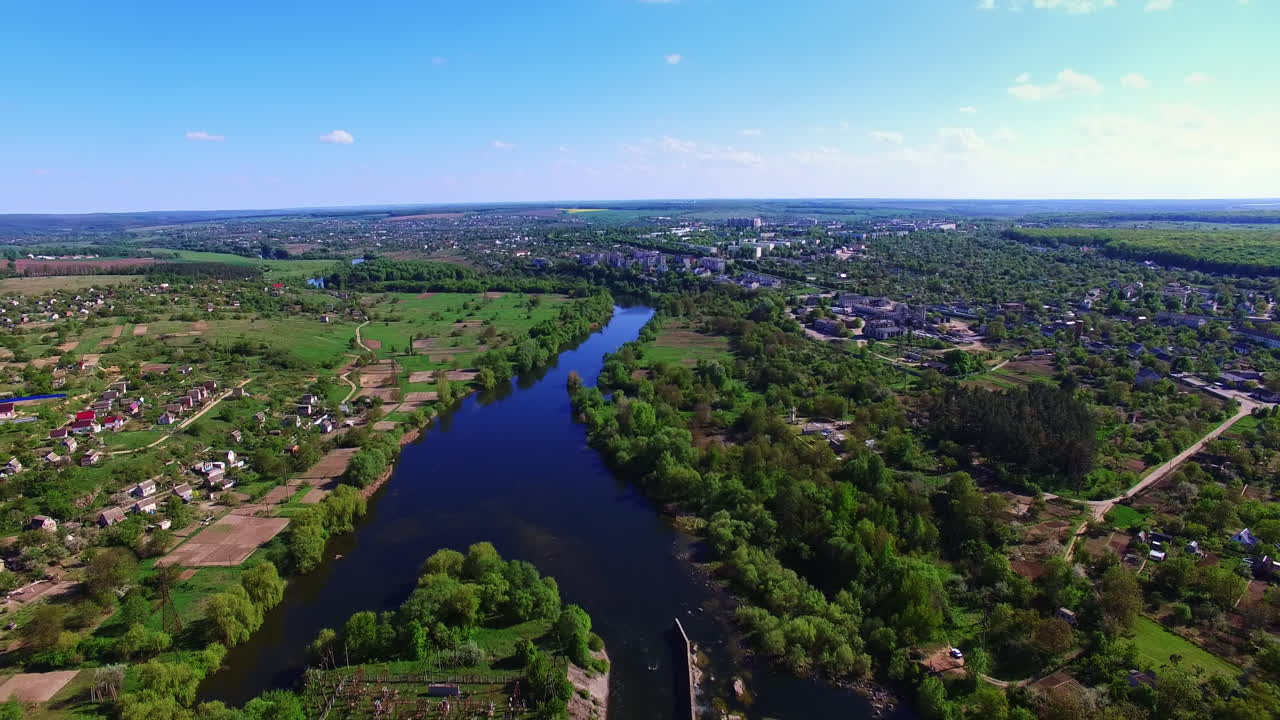Blue river floating through the green city on sunny summer day. Urban landscape with water artery from aerial perspective.