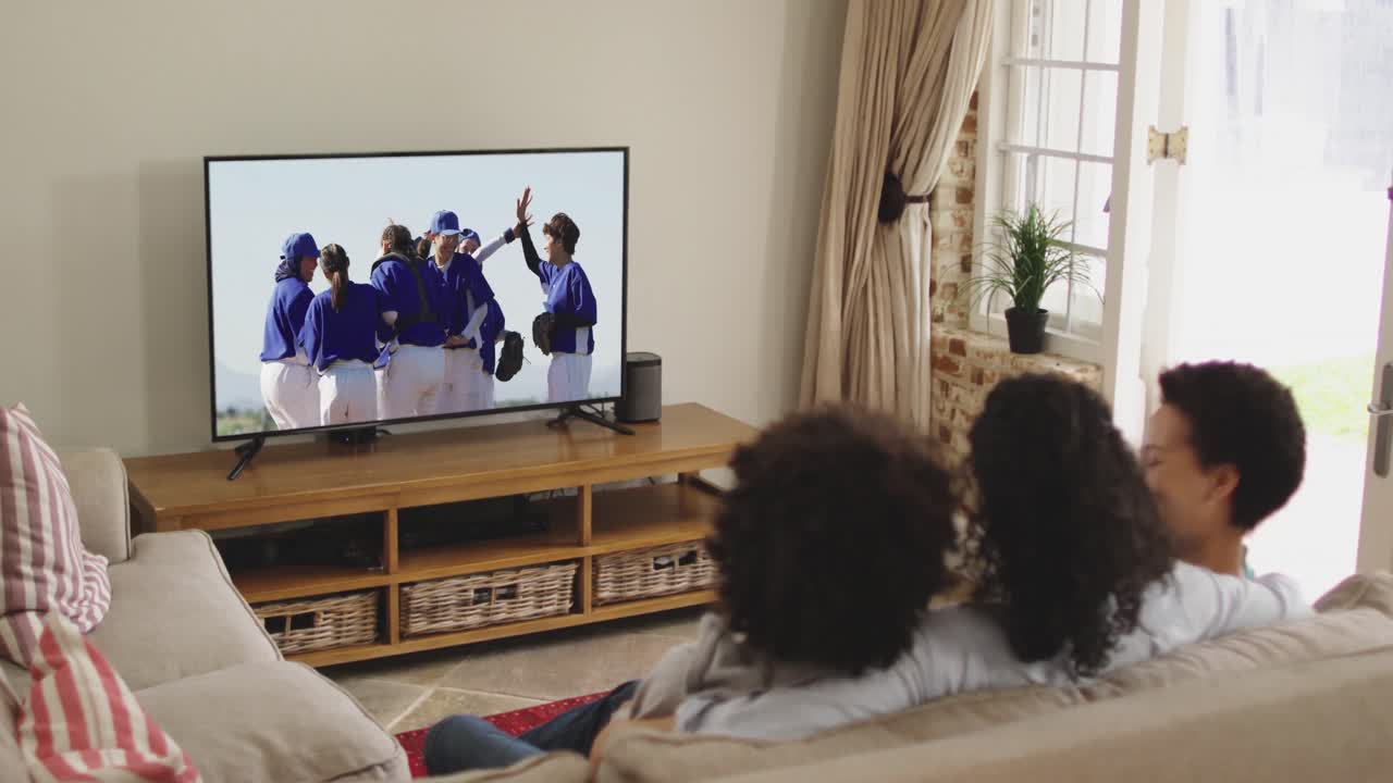 Famiglia felice seduta a casa insieme che guarda una partita di baseball in TV