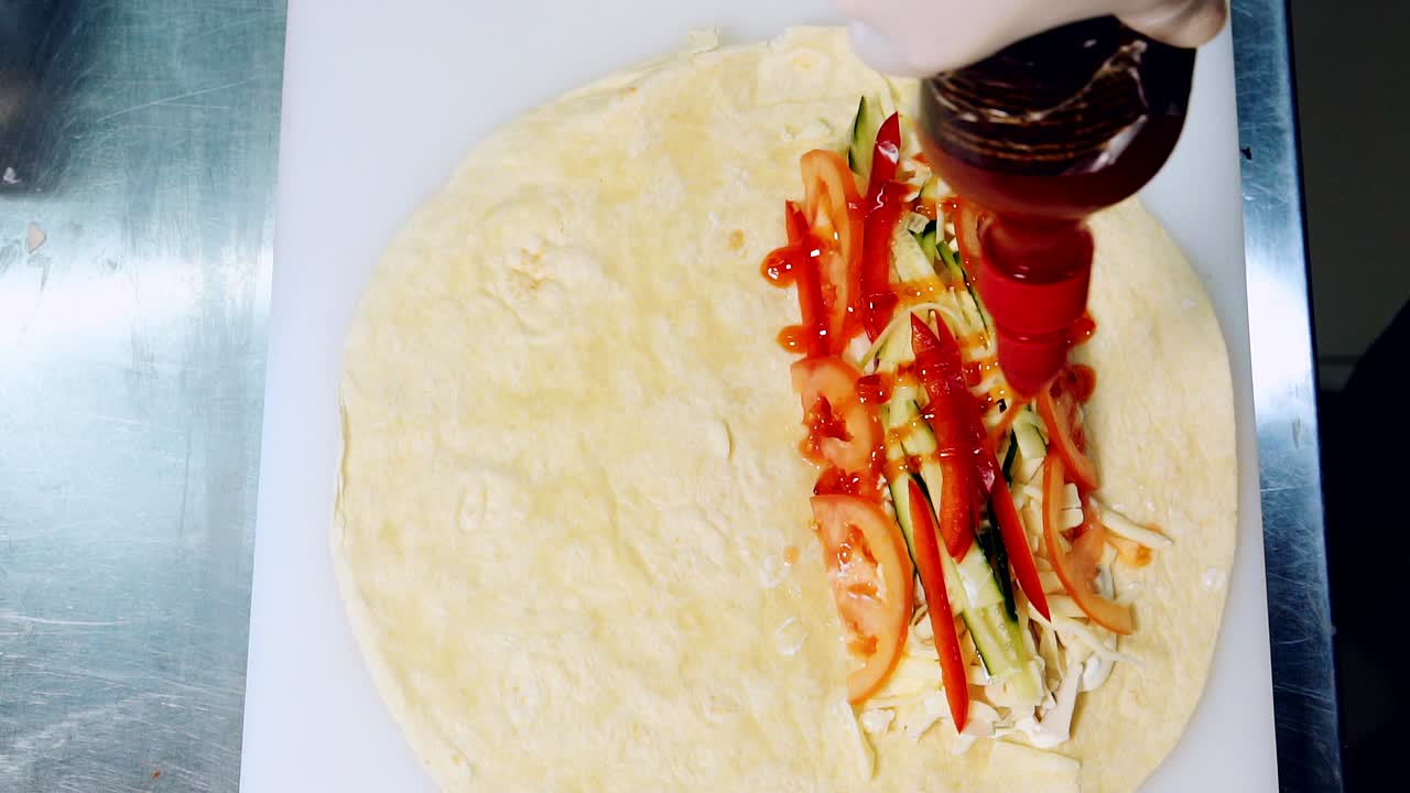 Preparation of delicious snack. Pouring red sauce on filling to cook pita. Chef adds ketchup into meat and vegetable pita. Top view