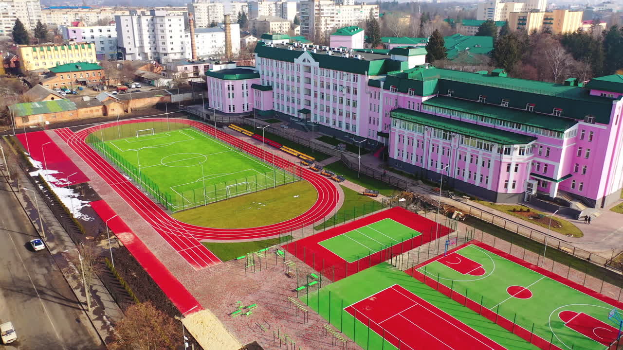 New fields for sports in the city. Sports complex with a modern stadium. Outdoor playgrounds on the urban background. Aerial view.