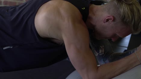 hombre musculoso en el gimnasio en casa ejerciendo tablones en balón medicinal