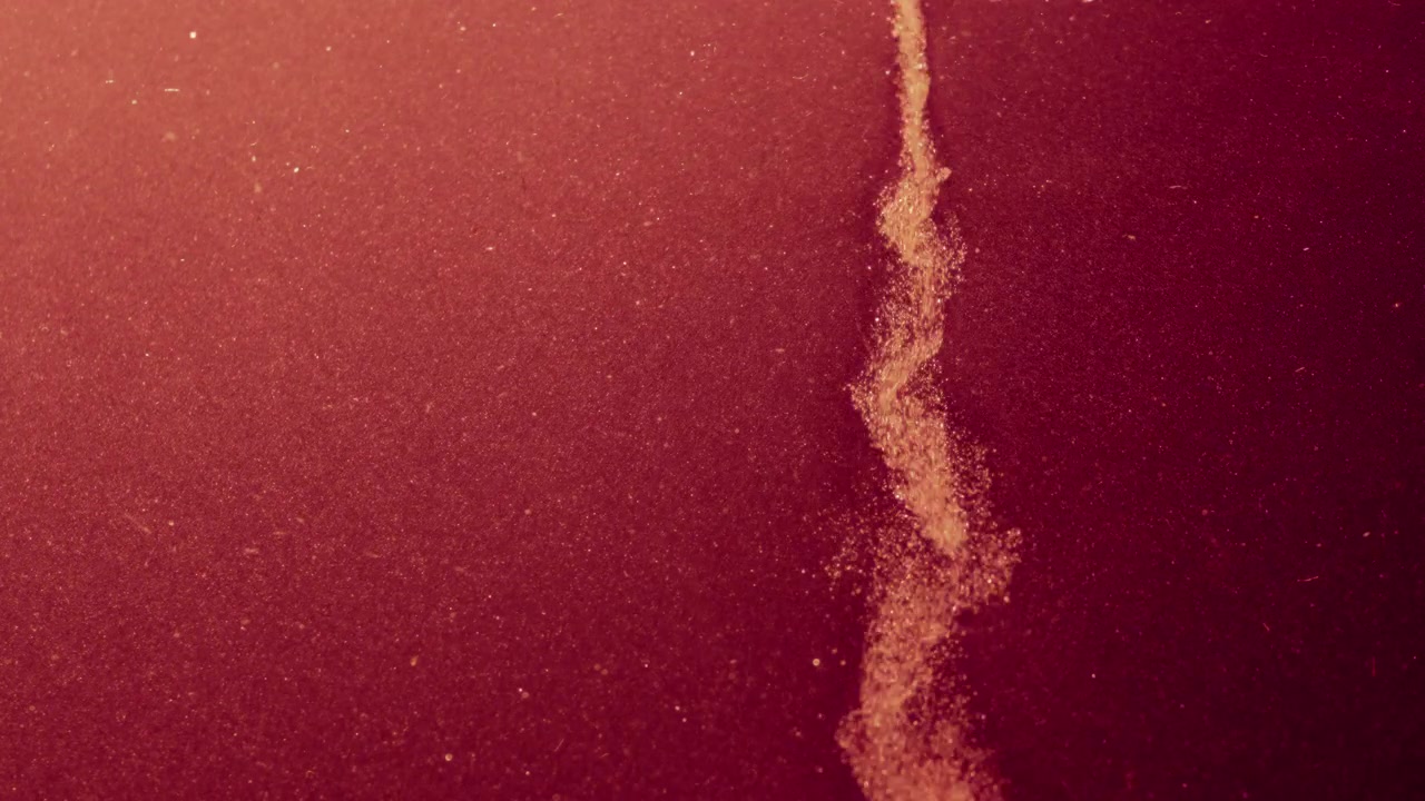 Abstract red grainy particles falling in slow motion