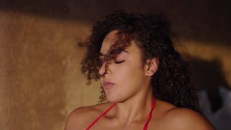 a woman with curly hair in a state of relaxed sensuality