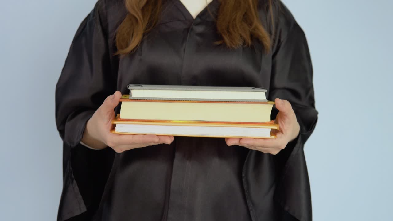 검은 옷을 입은 백인 여성 학생의 손에 수평 위치에 있는 여러 교과서.