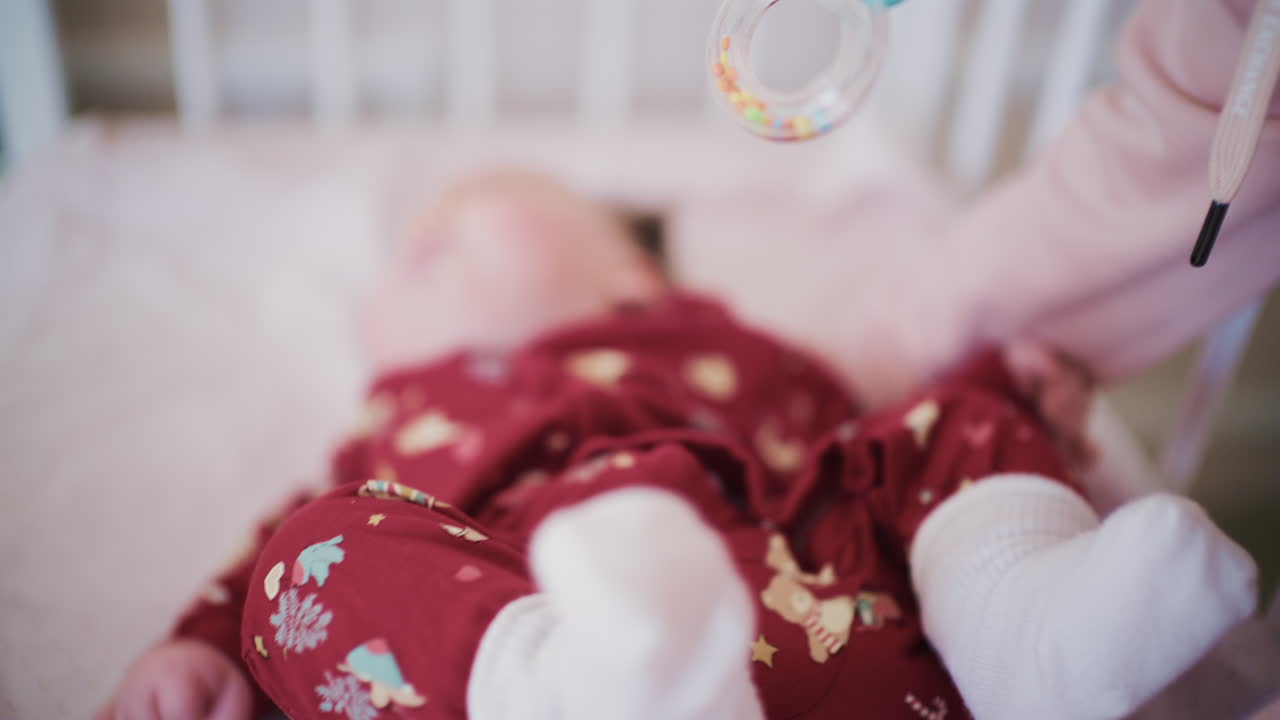 Un neonato viene adagiato e giace in una culla, muovendo delicatamente le gambe coperte da morbidi calzini bianchi.