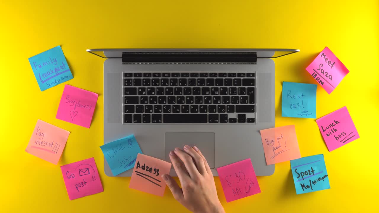 Use laptop, post it papers on workspace, making notes on stickers, yellow desk
