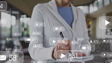 animación de iconos de las redes sociales flotando contra una anciana caucásica tomando notas en casa
