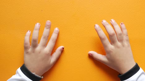 top view of child moving her finger on orange background