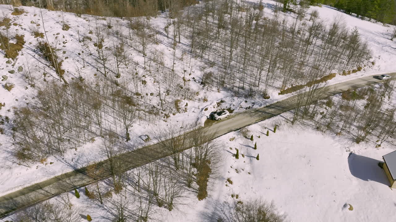 Aerial View of Snowy Mountain Landscape with Road and Cabins