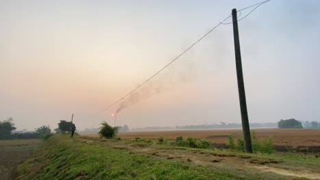 Bangladeshi-young-man-jogging-outdoor-in-rural-countryside,-Industry-behind