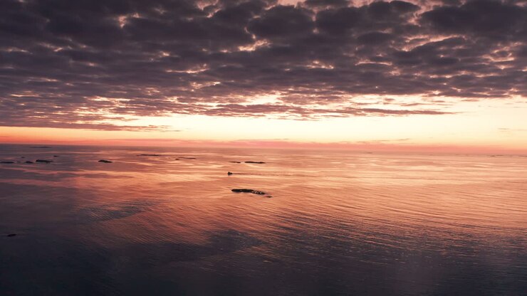 A picturesque landscape of a pink-hued sunset over still waters, creating a serene and peaceful atmosphere