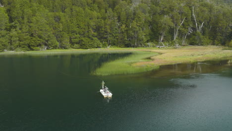 Stunning-aerial-shot-of-two-people-fishing-off-a-small-boat-on-the-Manso-River,-Argentina