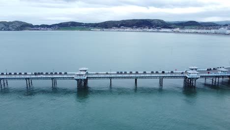 Llandudno-pier-historic-Victorian-wooden-boardwalk-seaside-landmark-aerial-view-pan-left-looking-down