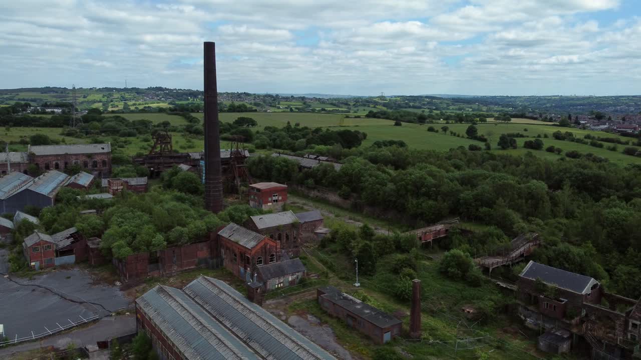 Forladte, gamle, tilgroede, rustende industrimuseumsbygninger fra en kulmine; luftoptagelse, der kredser mod højre.