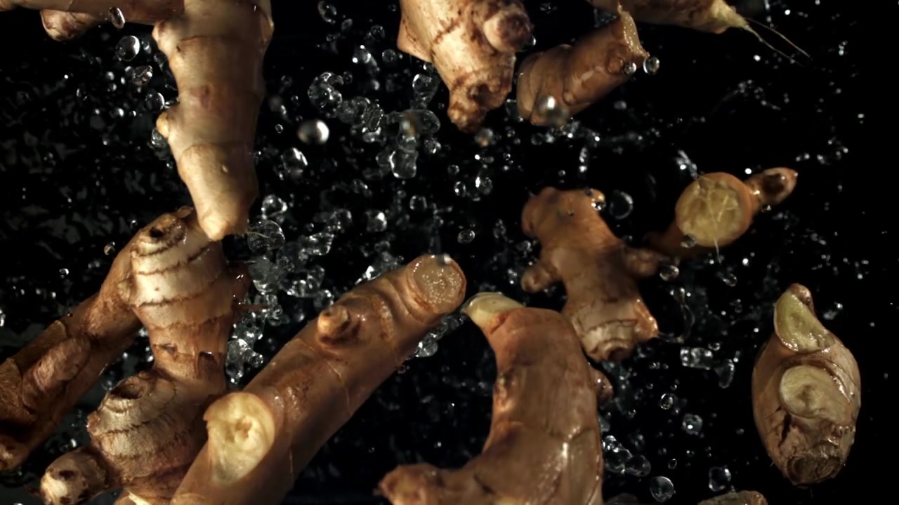 Fresh Ginger Roots with Water Splashing on Black Background
