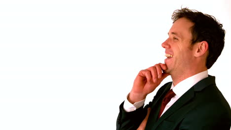 un hombre de negocios feliz riendo con la mano en la barbilla.