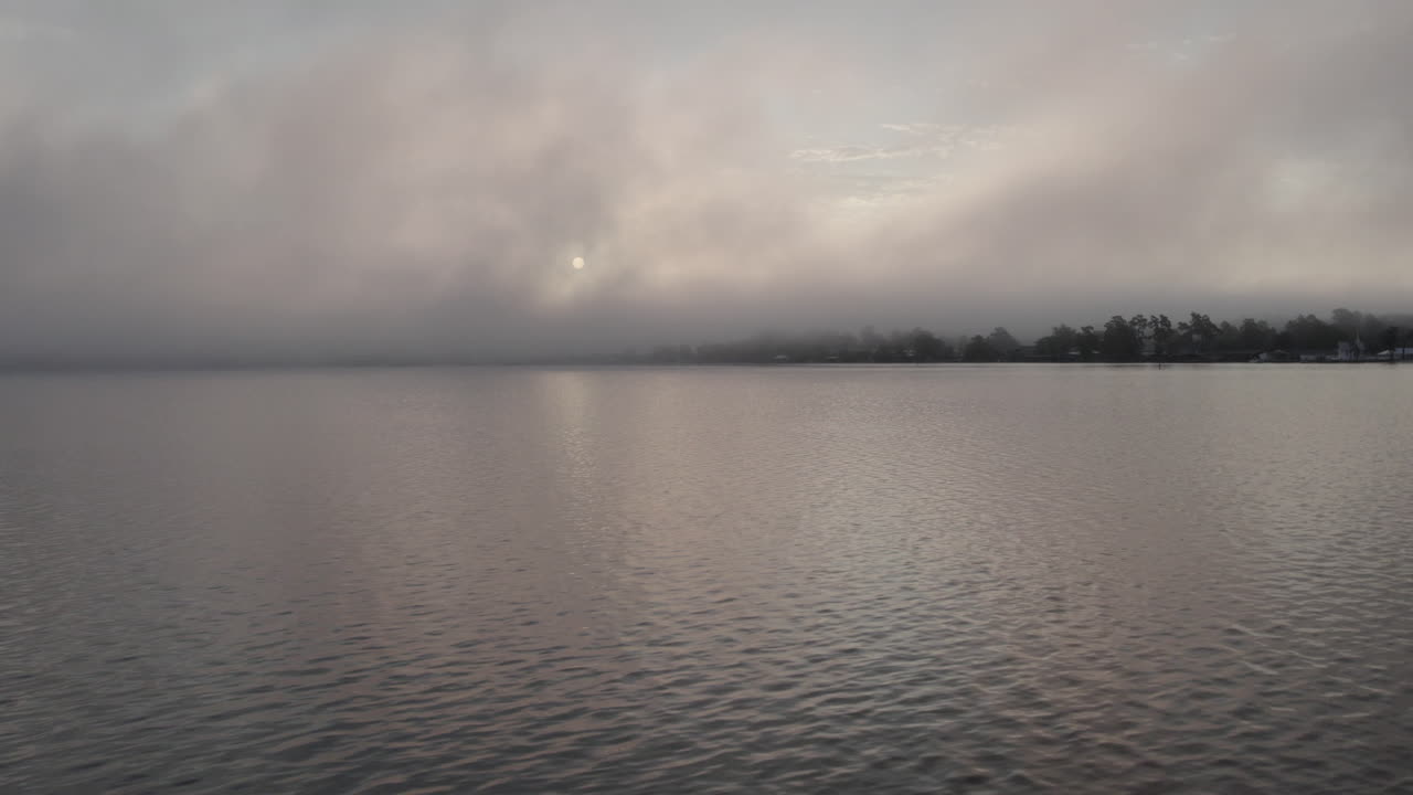 Drone shot of sunrise on a fogging morning on a lake