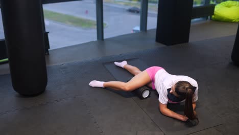 Woman foam rolling her legs in a gym