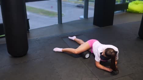 woman foam rolling her legs in a gym