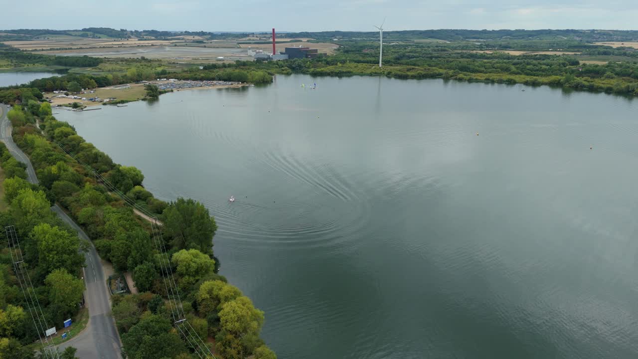 Aerial drone footage capturing water sports including powerboating, sailing, and skiing on a Bedford England UK lake with lush green surroundings
