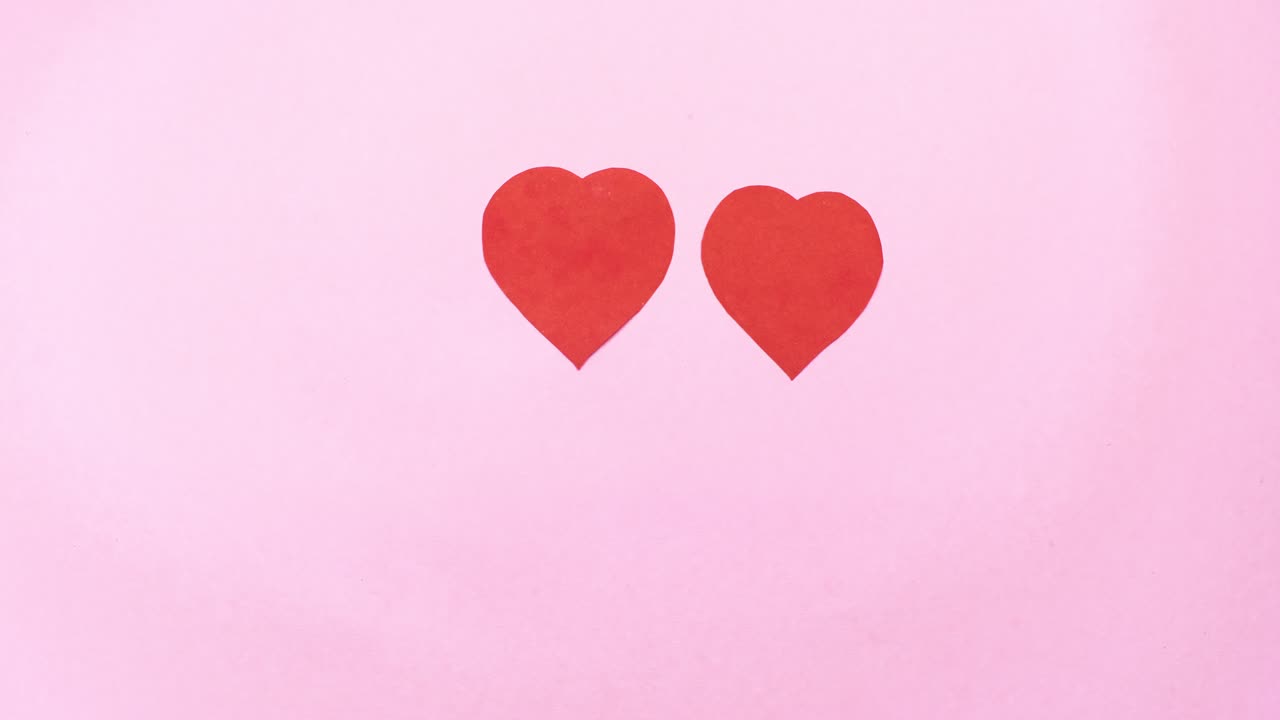 4k 두 개의 빨간색 심장이 축에 둥글고, 밝은 분홍색 배경에 고립되어 있습니다.