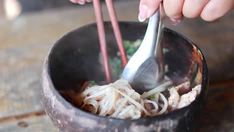 saboreando fideos de cerdo en un cuenco de cáscara de coco
