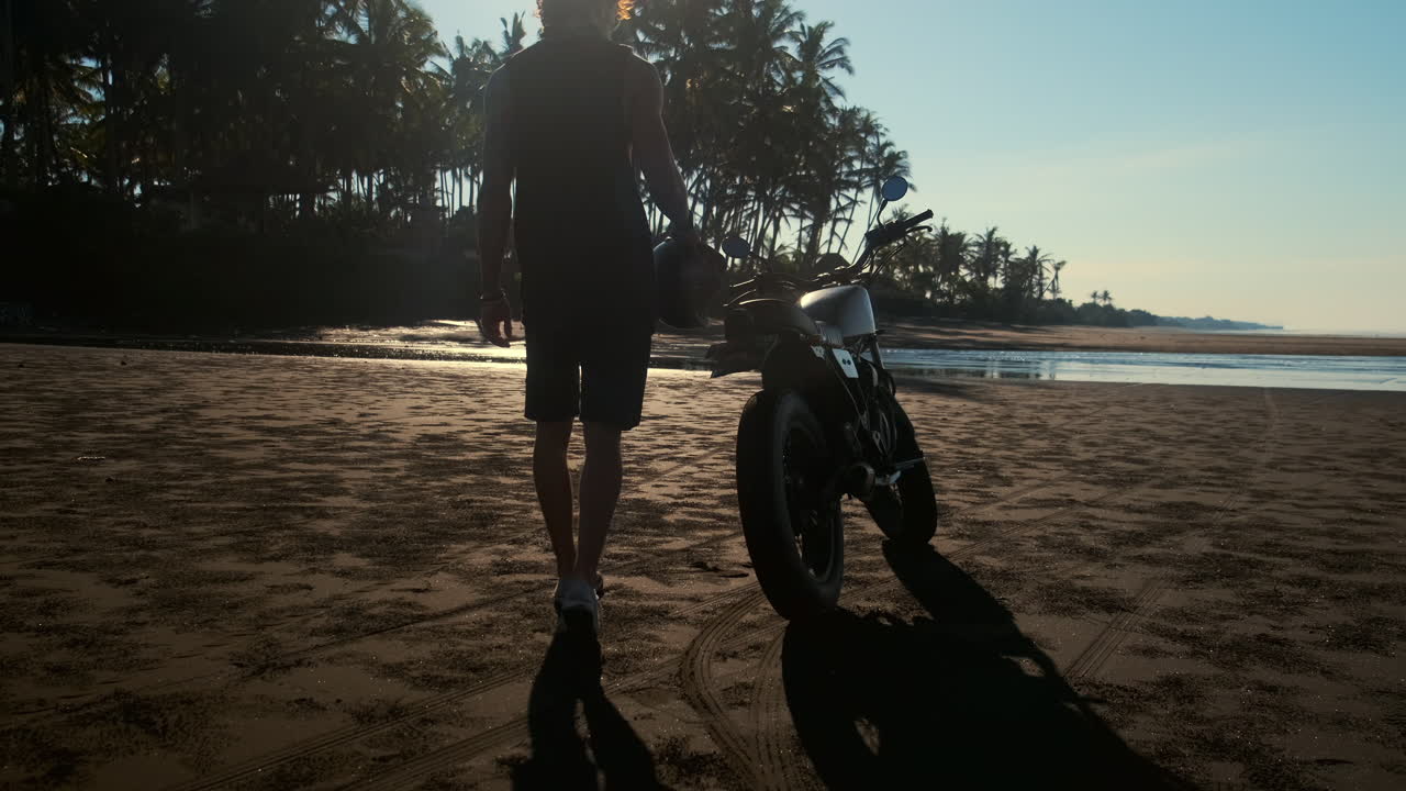 Man on a Motorcycle on a Tropical Beach at Sunrise