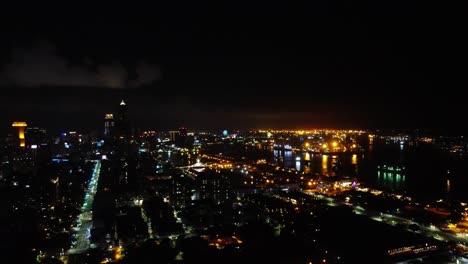 Nighttime-aerial-view-of-a-vibrant-cityscape-with-illuminated-streets-and-buildings