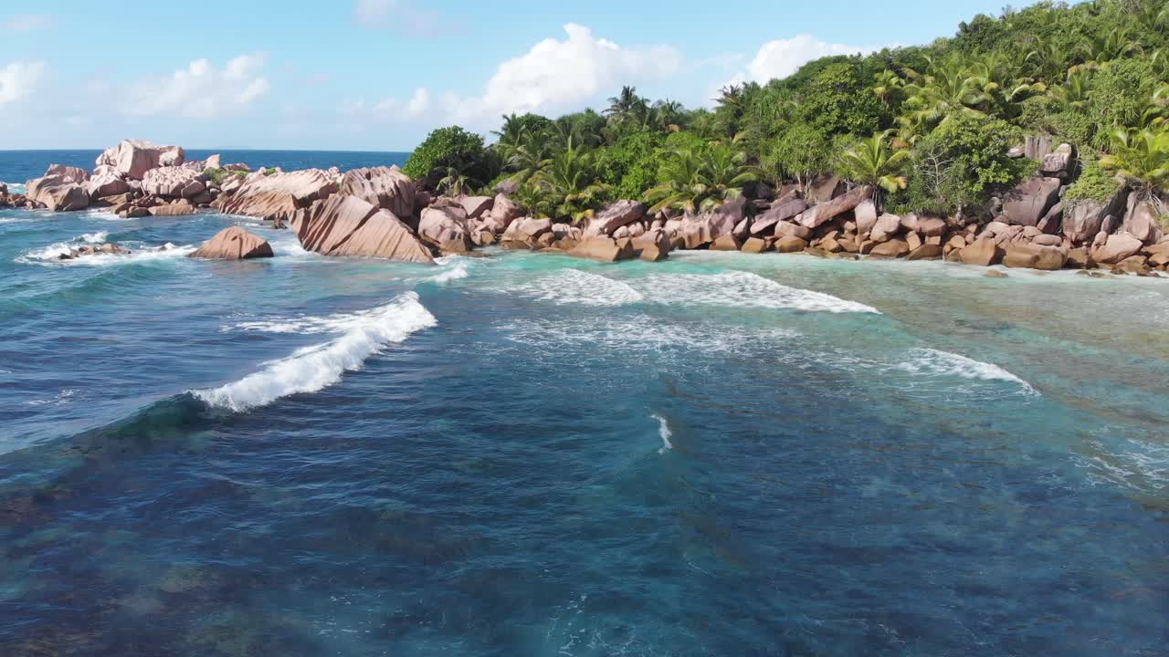 vista aérea siguiendo las olas rodando hacia las playas blancas y despobladas de anse coco, petit anse y grand anse en la digue, una isla de las seychelles