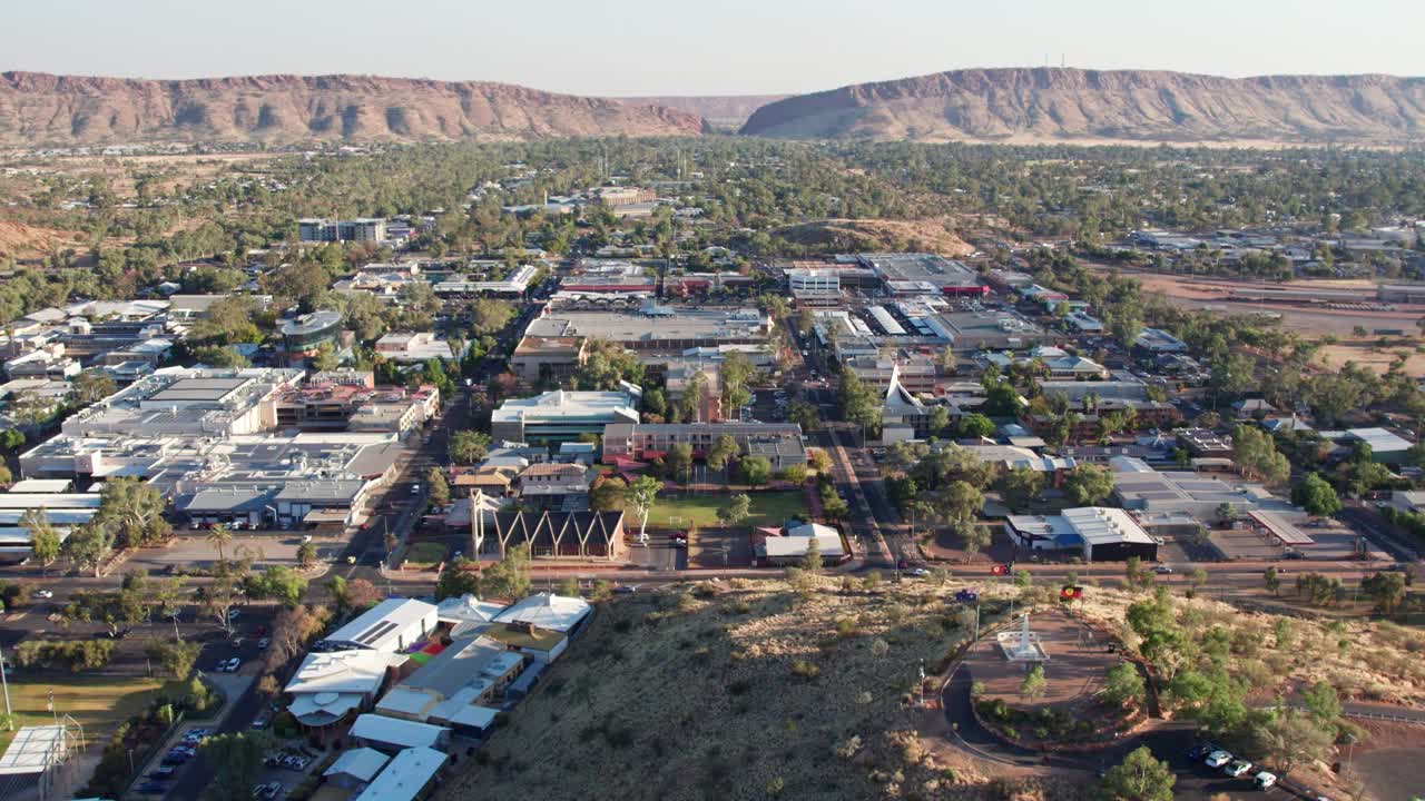 Aerial footage moving sideways of Anzac Hill and the town of Alice Springs, Mparntwe, with MacDonnell Ranges in the distance. Northern Territory, Australia. August 2022.