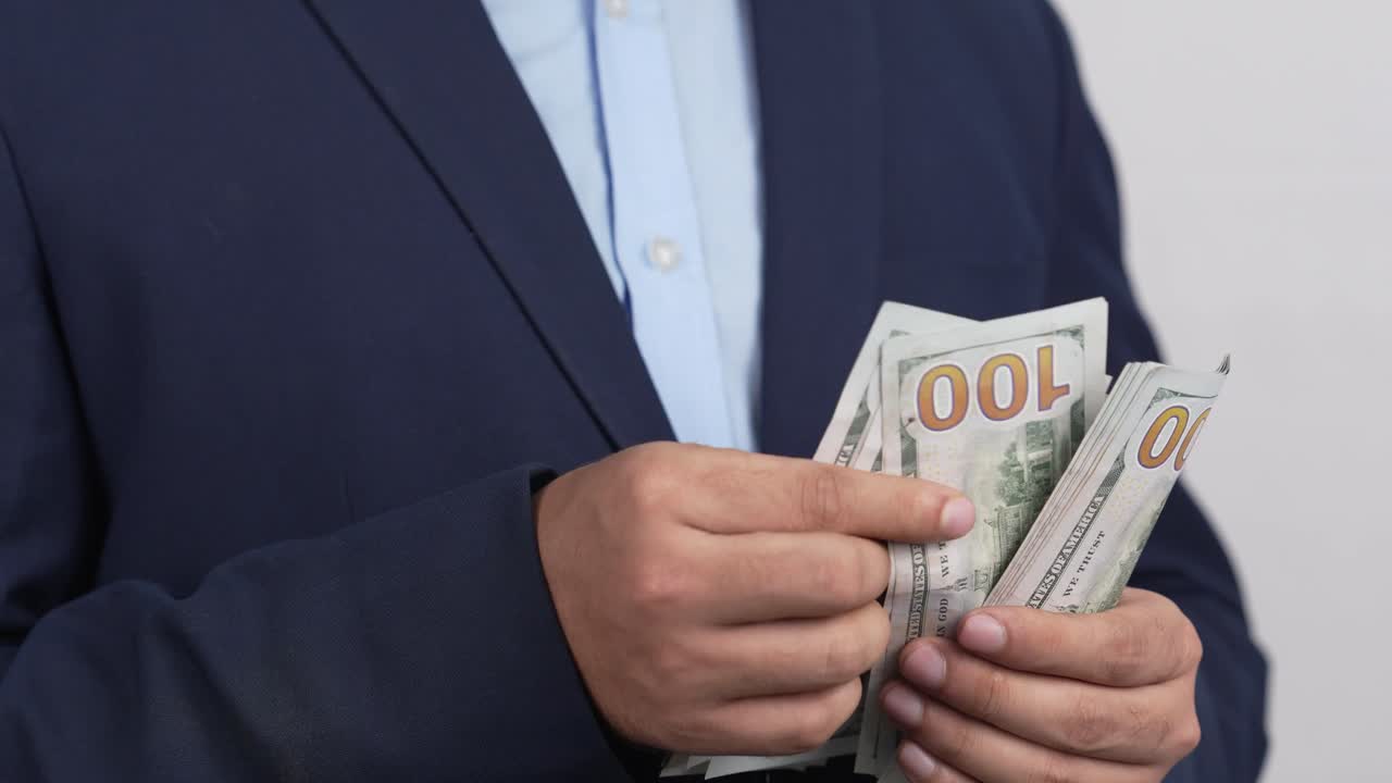Pengusaha memegang uang tunai dolar AS di tangan, konsep kekayaan finansial, Video 4K