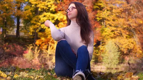 cámara lenta de una adolescente en un colorido paisaje otoñal, hoja de árbol amarilla, estanque en un día soleado de otoño