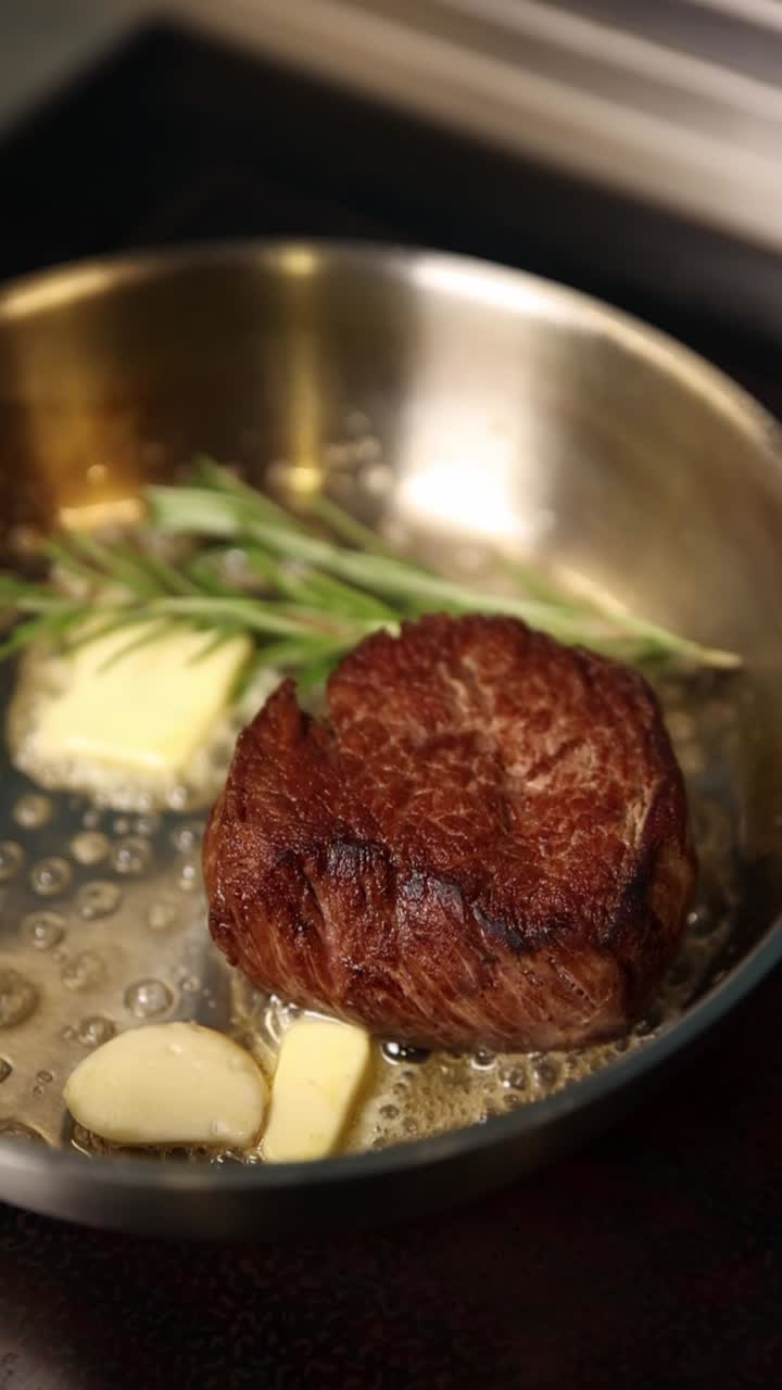 Steak cooking in a pan with butter and rosemary