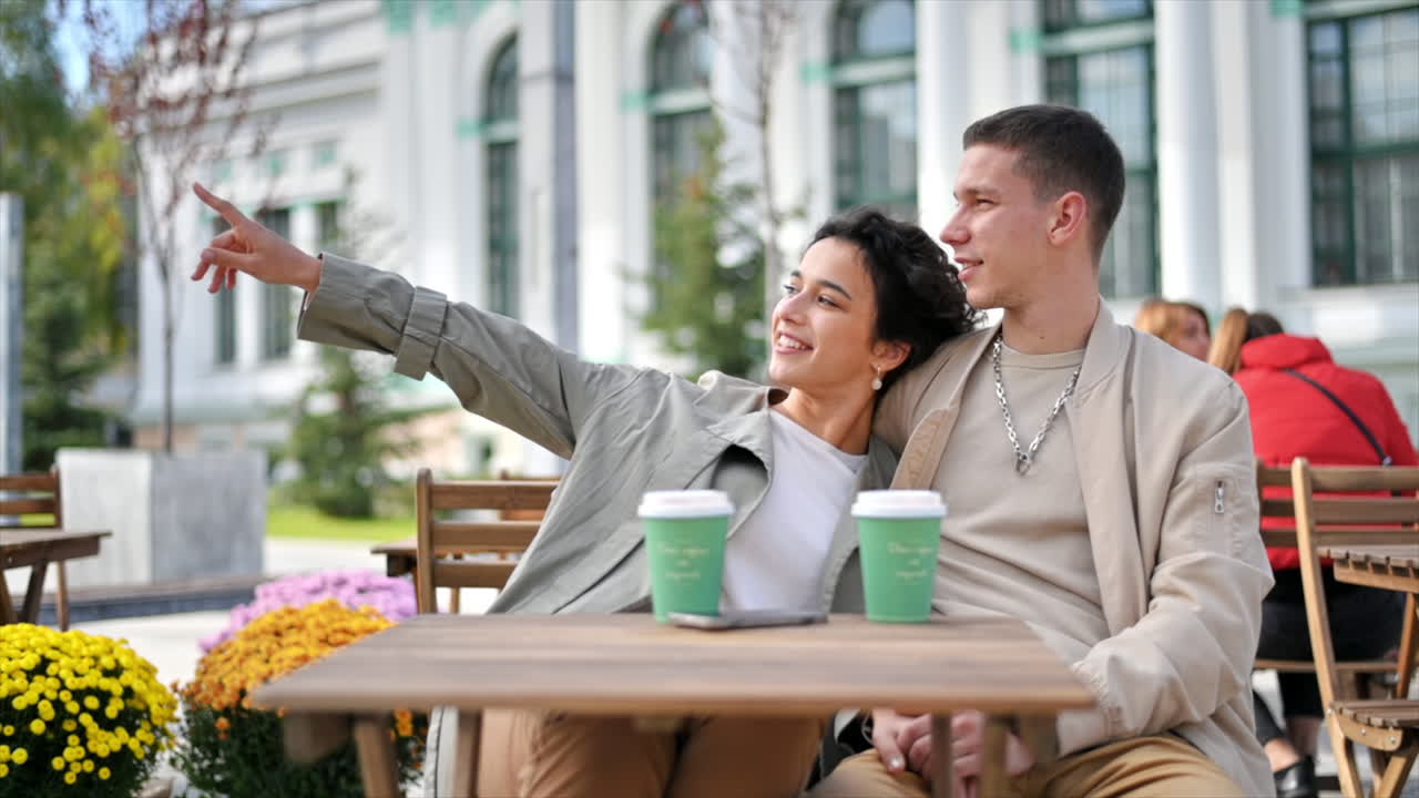 A happy couple outdoors near a cafe. Hugging each other, smiling and talking, coffee. Autumn atmosphere. Slow motion