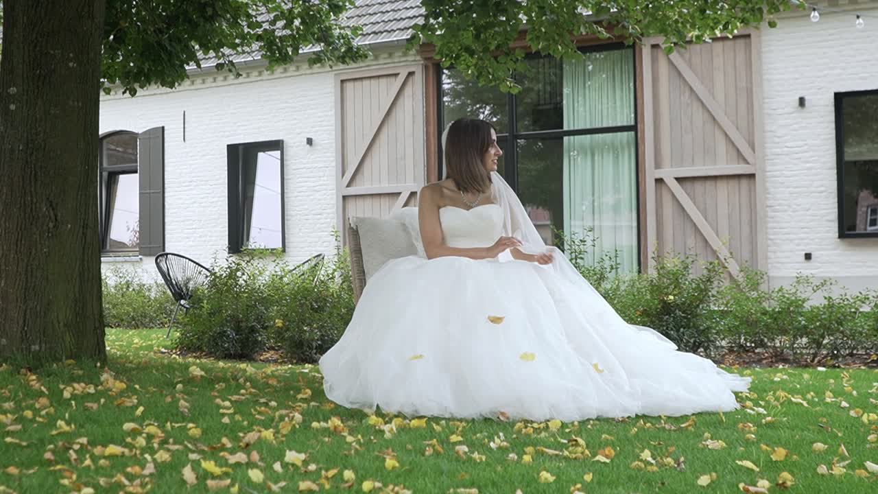 Bella sposa nel suo abito da sposa seduta in giardino