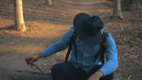 explorer sticking a knife unto a log