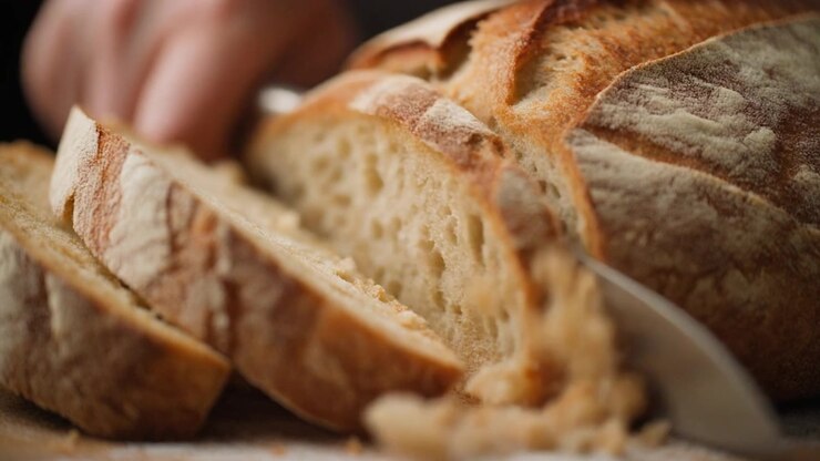 Person Slicing Fresh Crusty Sourdough Bread with a Knife