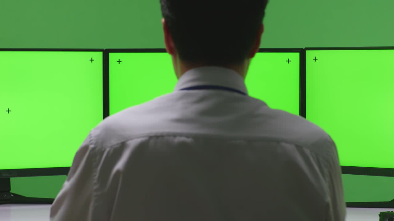 여러 모니터가 있는 제어실에서 일하는 사람