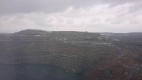 aerial shot from a plane of thetford mine, québec while its snowing and cloudy