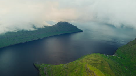 Aerial View of a Fjord with Green Mountains and Fish Farms under Cloudy Skies